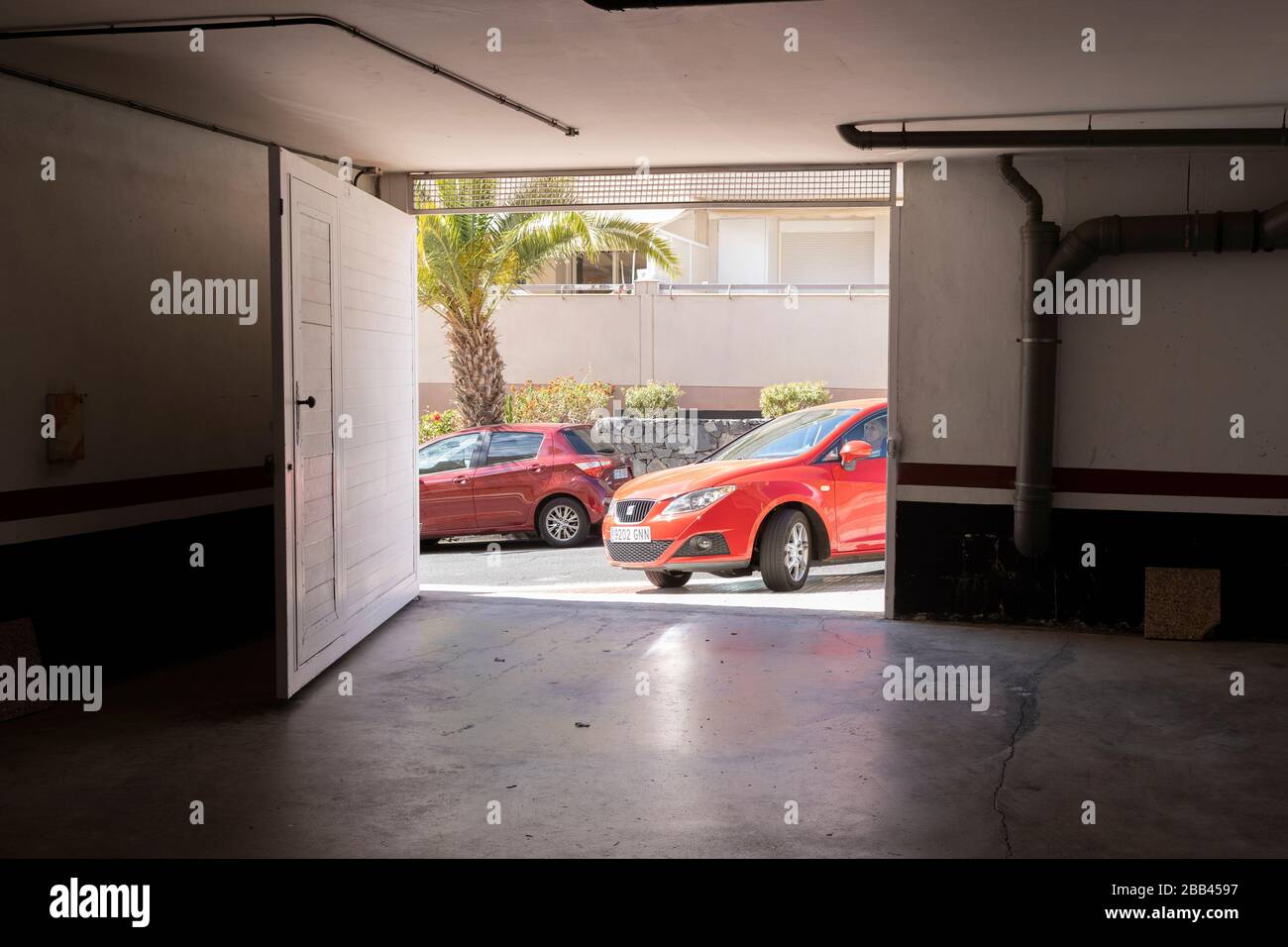 A red Seat Ibiza car turns into an underground garage from the street, Playa San Juan, Tenerife Stock Photo
