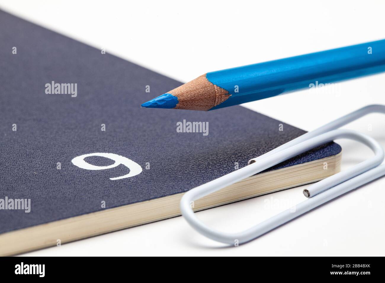 Organizer for the month of September, blue pencil and white paperclip on the white table. Stock Photo