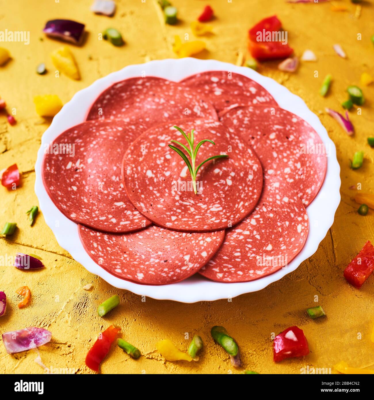 closeup of some slices of veggie salami in a plate, on a golden textured surface Stock Photo