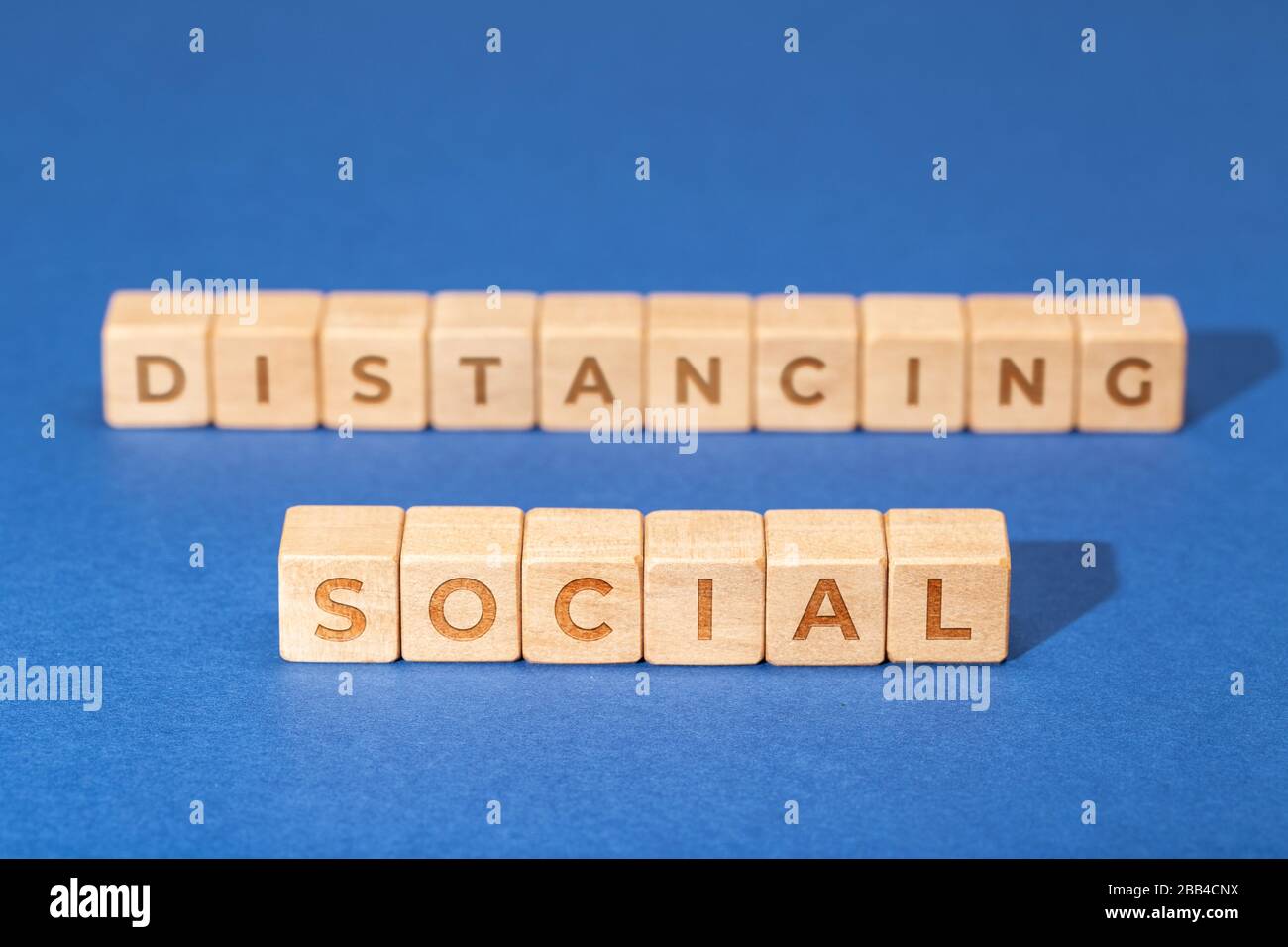 Social distancing concept. Wooden dices isolated on blue background. Coronavirus COVID-19 outbreak advice Stock Photo