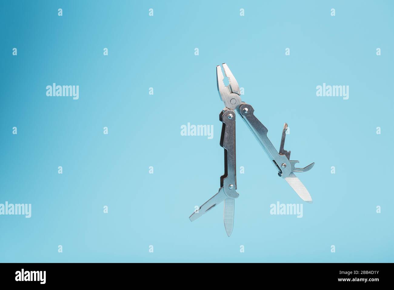 The multitool multi-function tool hovers on a blue background. The concept of an expanded multi-tool with free space. Stock Photo