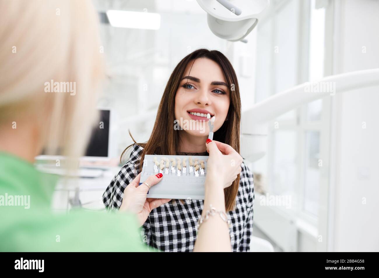 Beautiful young woman at dentist's office choose teeth color tone Stock Photo