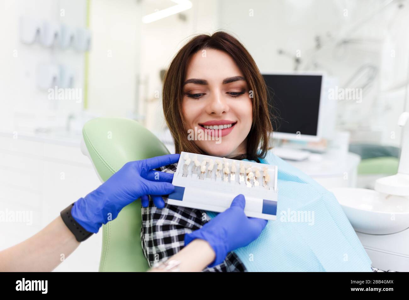 Dentist and his patient choose a tone of veneers. Dentistry doctor shows a palette with shades for teeth Stock Photo