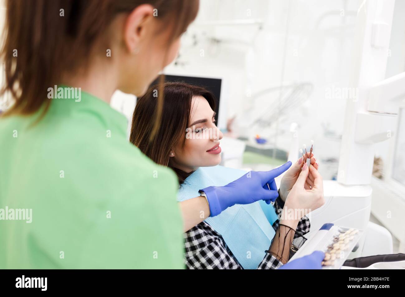 Dentist shows crown samples to his patient. Woman at the dentist's appointment chooses the tone of veneers Stock Photo