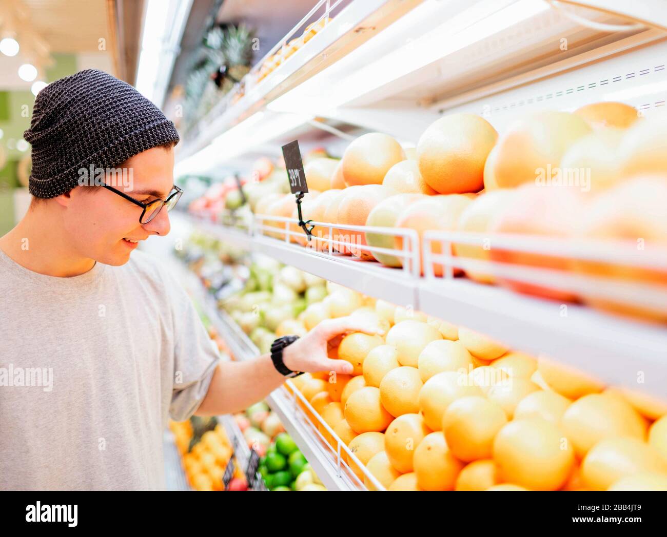 This should be fine. Handsome young men orange pepper and shopping bag while standing in a food store Stock Photo