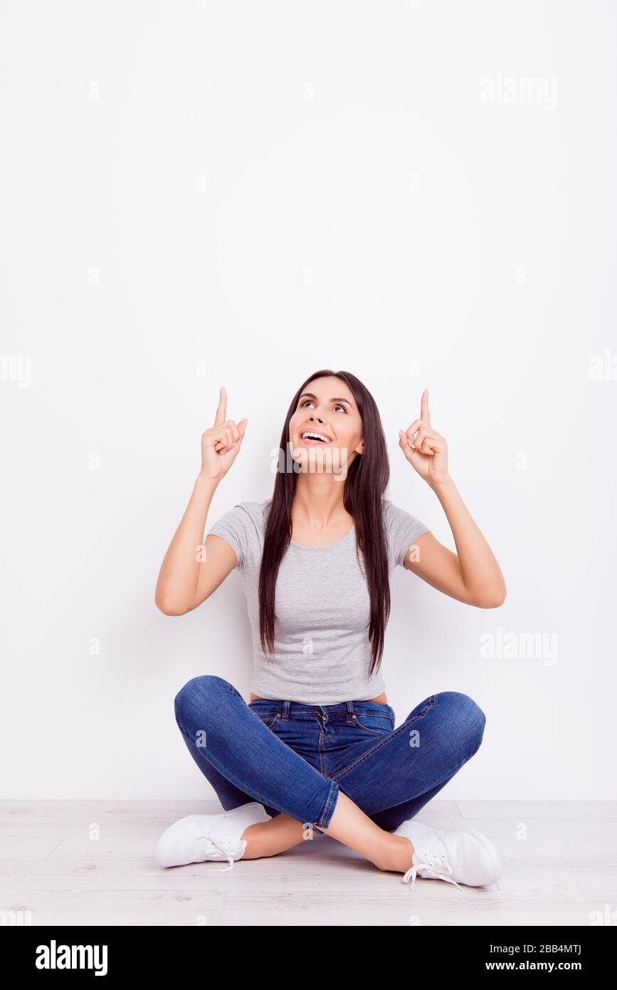 Young cute girl is sitting on the floor pointing with her fingers at ...