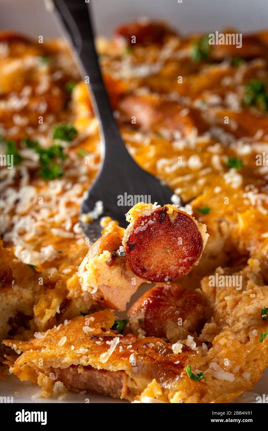 Eating fresh omelette with pork sausages, onion and gratted parmegiano Stock Photo