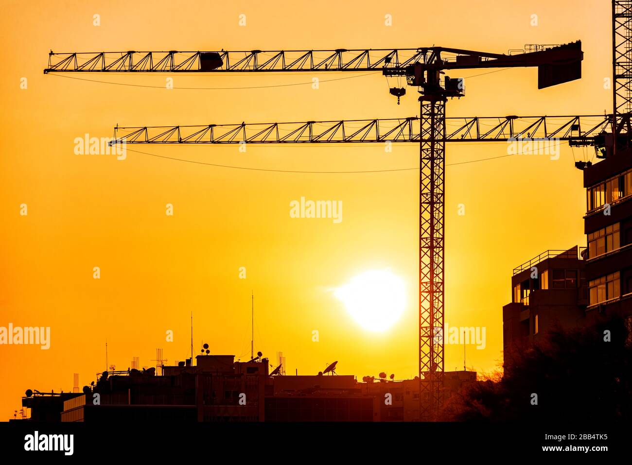 Silhouette of a construction cranes against sunset Stock Photo - Alamy