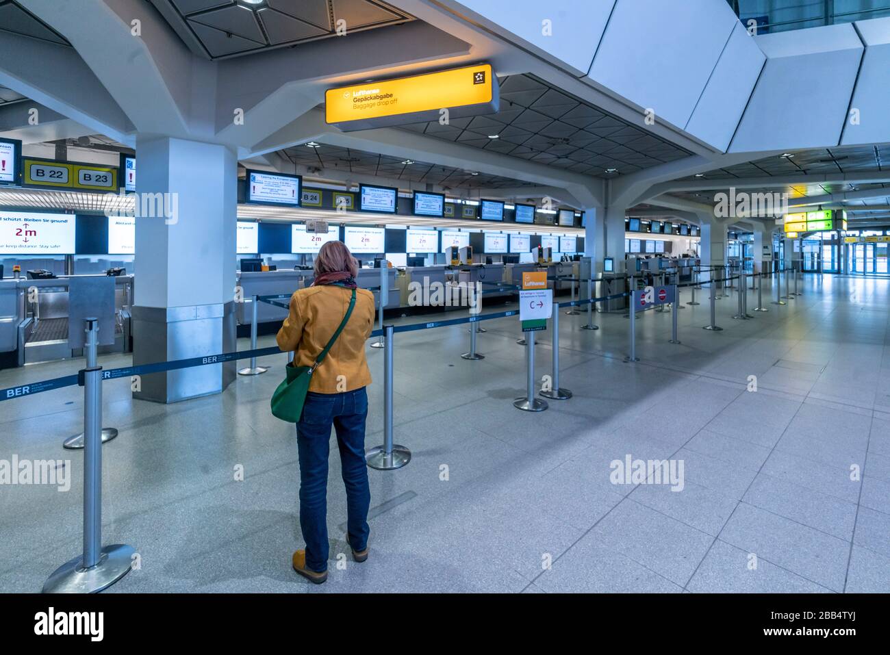 Frau vor menschenleerer Gepäckabgabe im Flughafen Tegel Terminal A wegen Coronavirus Stock Photo