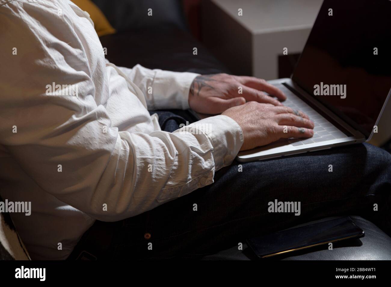 Close up of casual businessman working through a laptop at the table on sofa at home, student studying an online course, E-learning, telework concept Stock Photo
