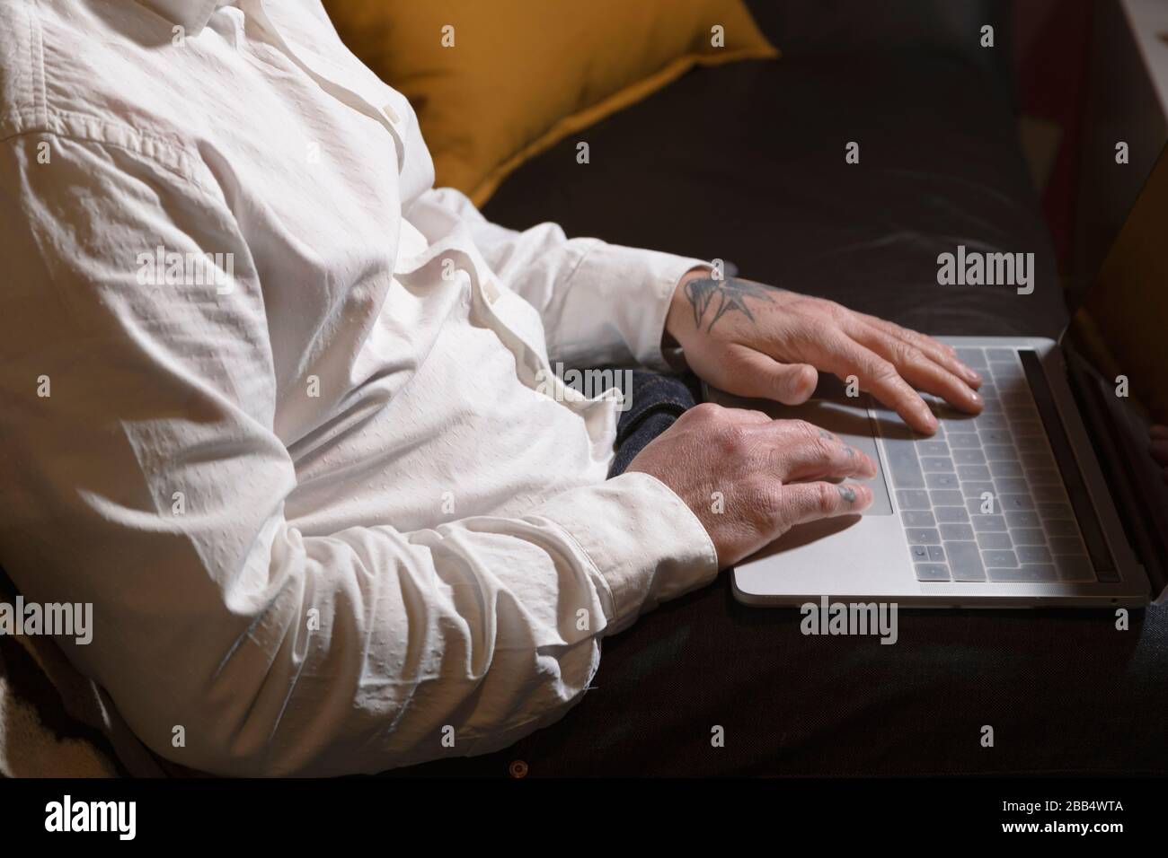 Closed shot of man working with laptop on sofa at home. Telework space on the sofa at home. Telework concept Stock Photo