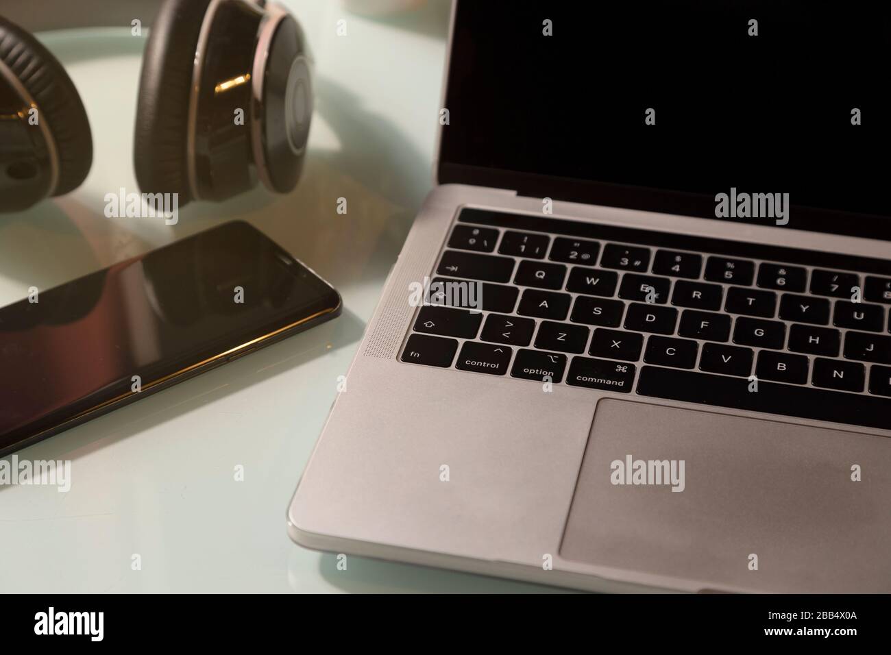 Headphones, laptop and mobile phone on the glass table. Top view Stock Photo
