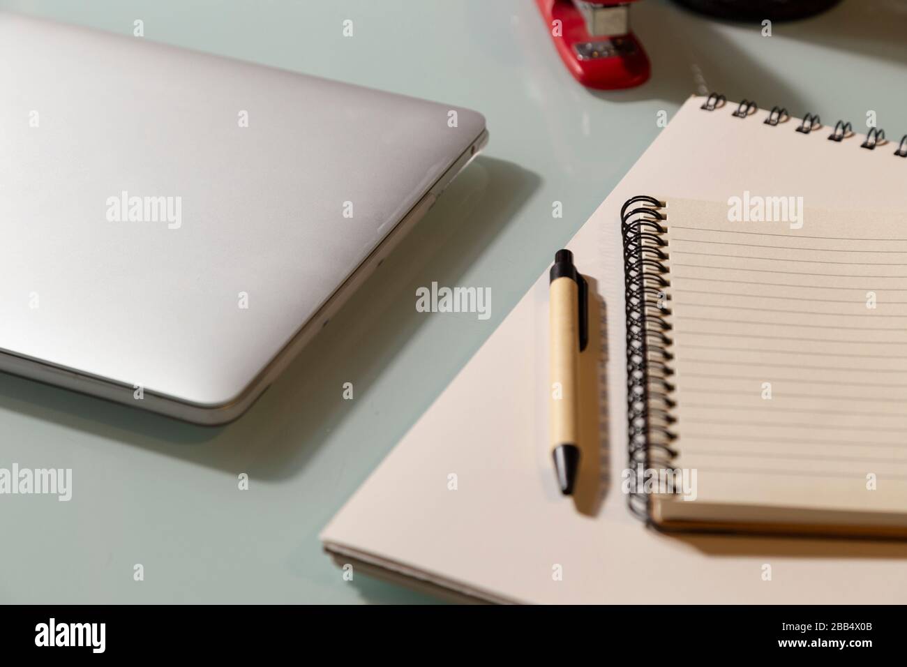 Notepad with pen and laptop on glass table. Selective focus. Telework concept Stock Photo