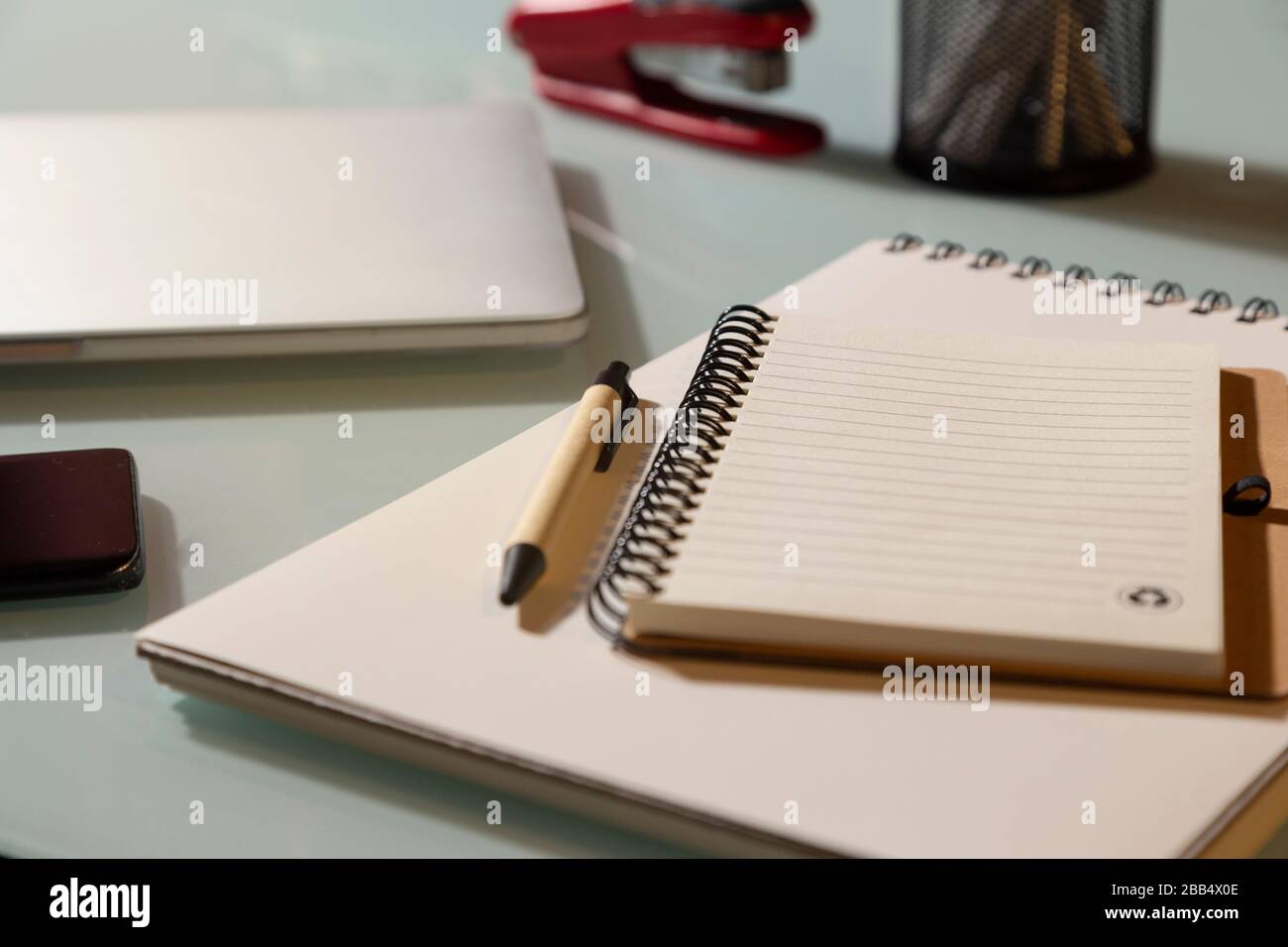 Notepad with laptop and mobile phone on glass table. Selective focus. Telework concept Stock Photo