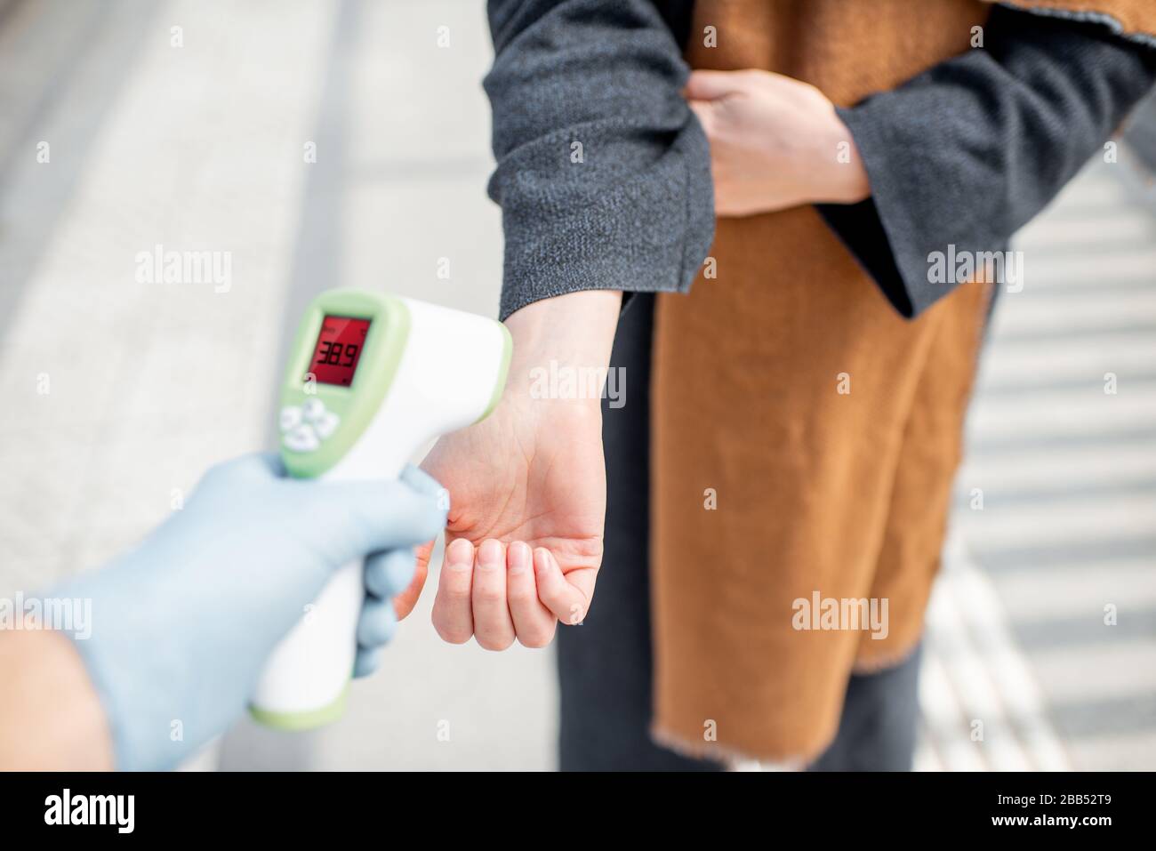 Measuring body temperature with infrared thermometer at a checkpoint during a virus outbreak, close-up on hand. Concept of prevention the spread of the virus Stock Photo