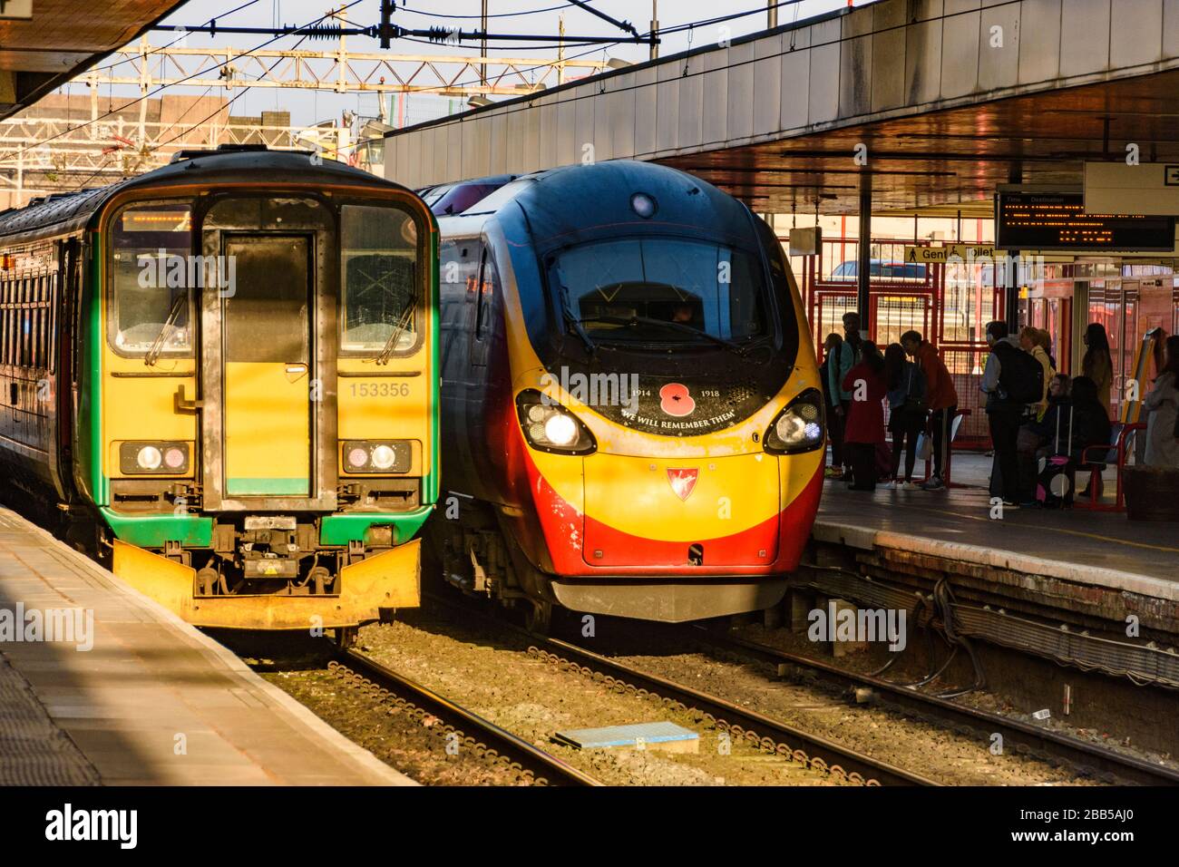 Virgin Trains Pendolino arrives at Coventry railway station next to a London Midlands Class 153 local service. Stock Photo