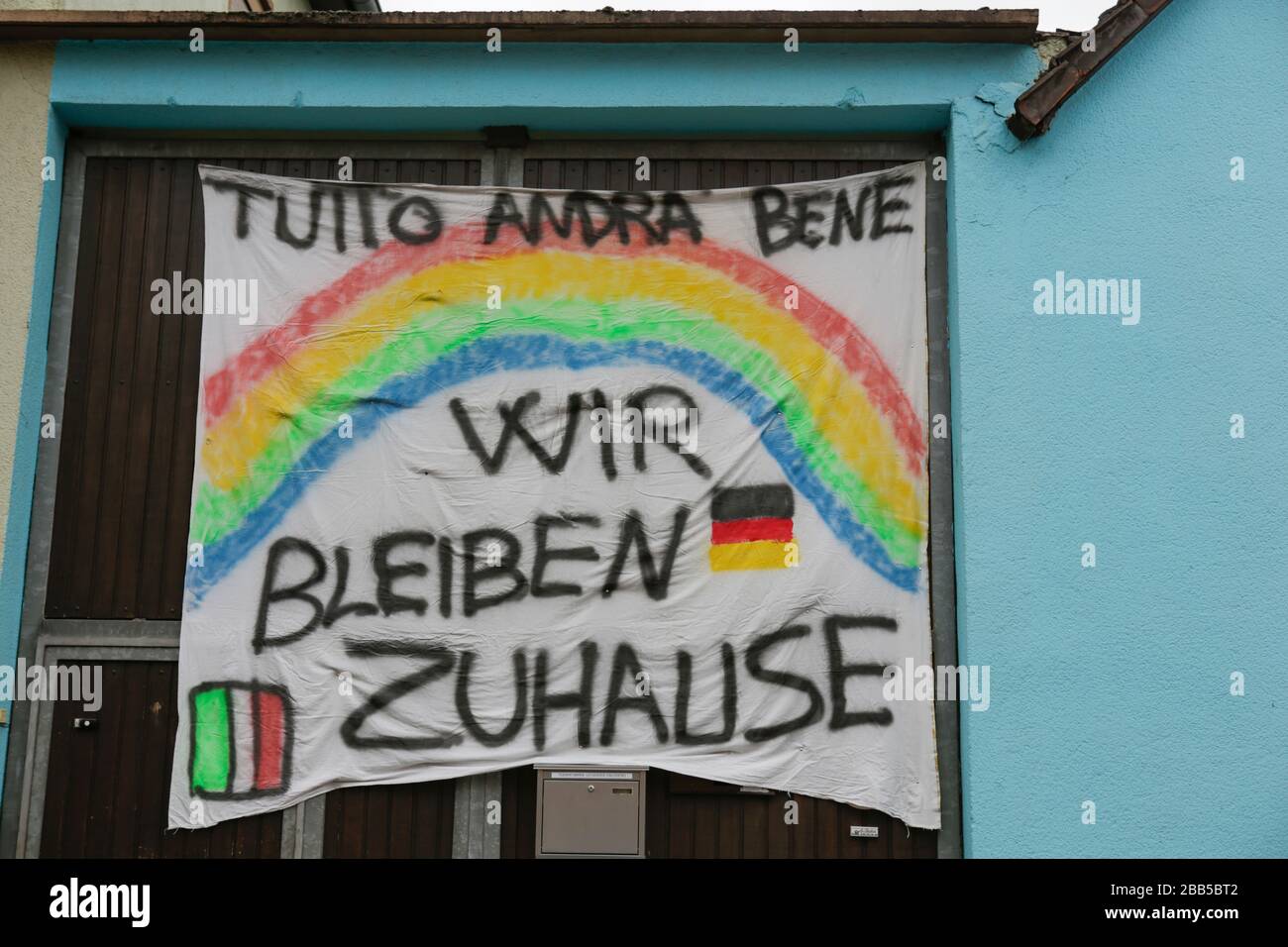 Worms, Germany. 29th March 2020. A large banner with a rainbow and “Everything will be oh” in Italian and “We stay at home” in German written on it, hangs on a house. While no curfew has been enacted in Germany during the current COVID-19 crisis, Germans are encouraged to stay at home and to limit meetings with people outside their household as much as possible. Stock Photo