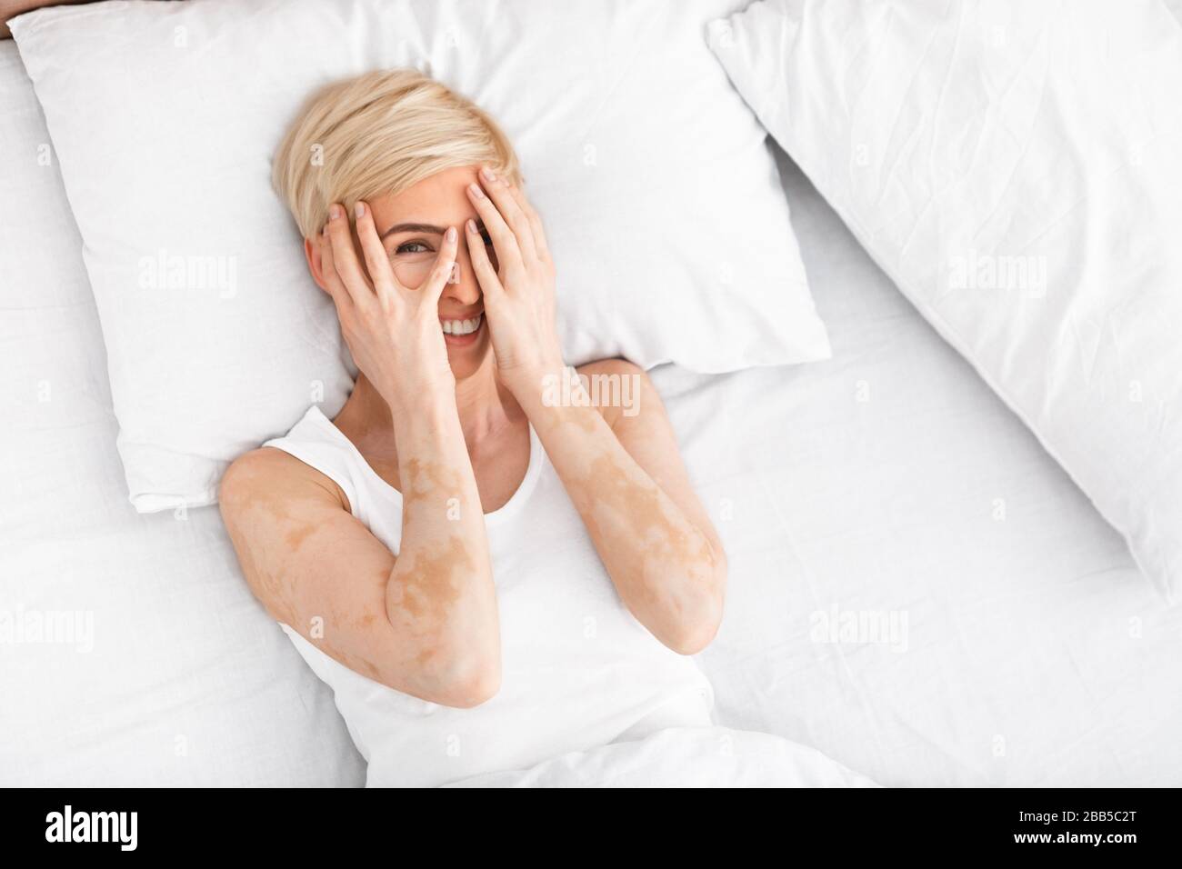 Middle aged woman playfully hiding her eyes behind her hands Stock Photo