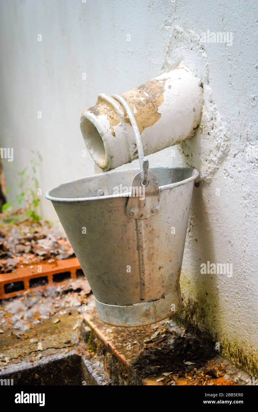 Vintage metal bucket hanging from an outside faucet Stock Photo