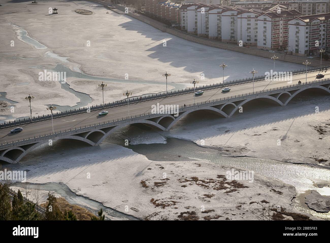 Aerial view of the bridge, frozen river and Chengde city downtown, Hebei province (China), in winter. Stock Photo