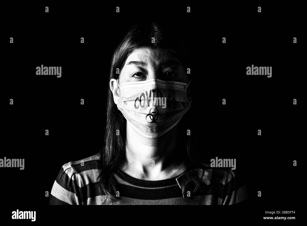 Woman with surgical mask. Biohazard and COVID-19, aka Coronavirus symbol. Pandemic or epidemic and scary, fear or danger concept. Black and White. Bla Stock Photo