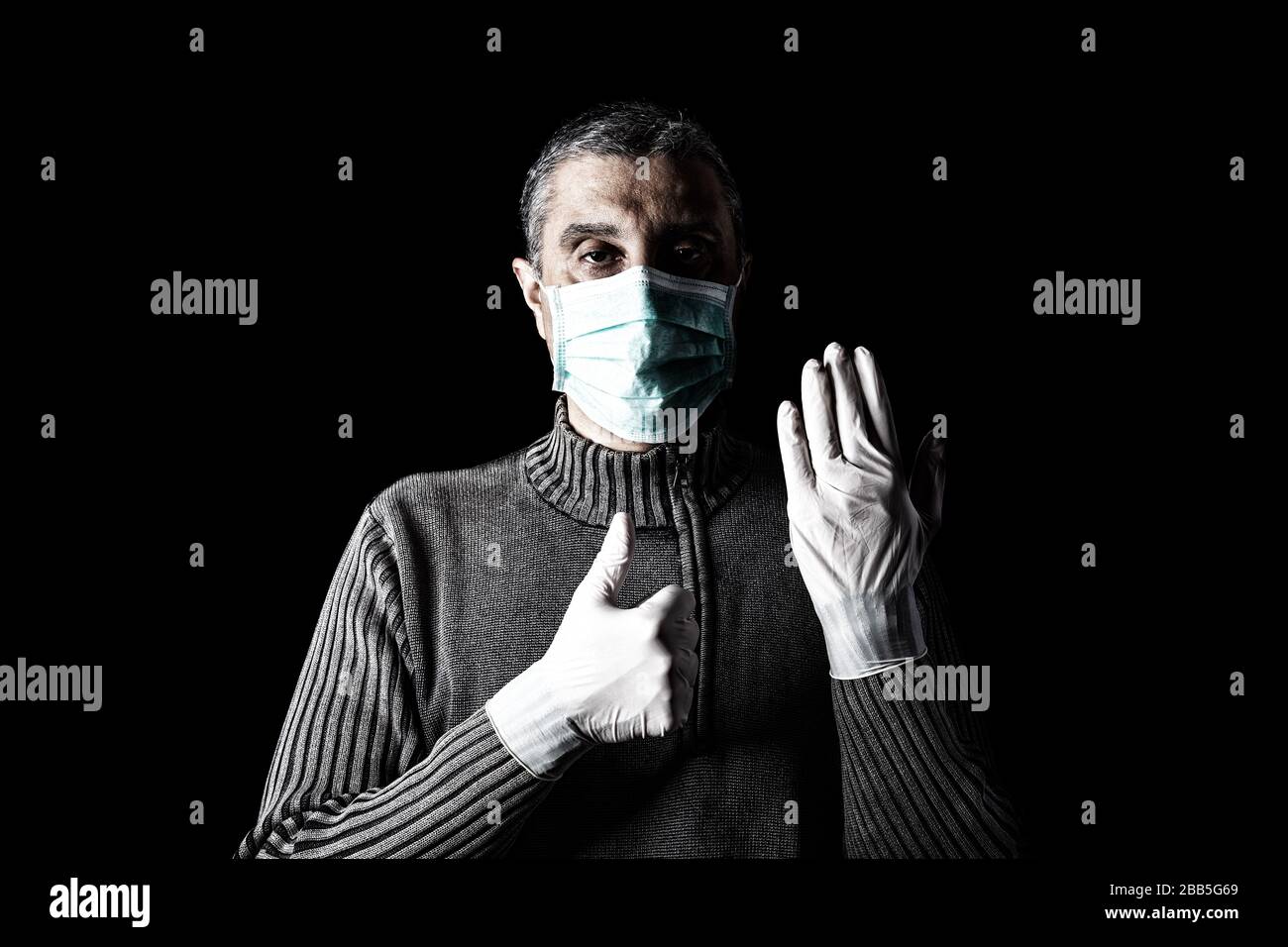 Man with surgical mask, protective gloves and thumbs up. Pandemic or epidemic and scary, fear or danger concept. Protection for biohazard like COVID-1 Stock Photo