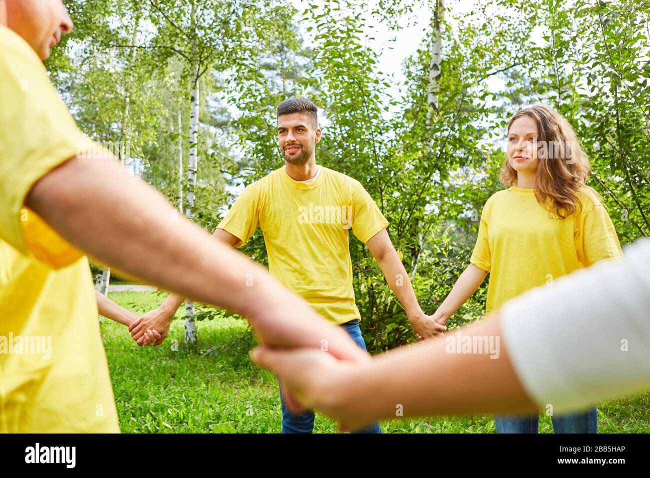 Group holding hands at team building event in nature Stock Photo - Alamy