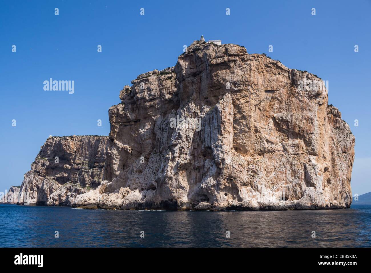 Calm blue water of Mediterranean sea, surrounding peninsula Capo Caccia  with a white building on the top of the cliff. Bright blue sky. Sardinia,  Ital Stock Photo - Alamy