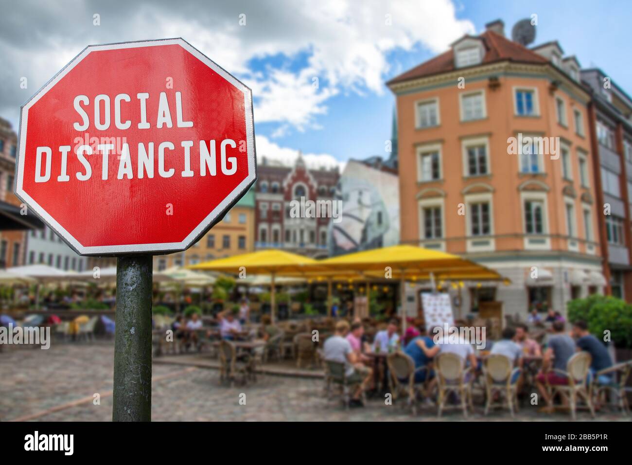 Social Distancing concept. Sign with social distancing word with cafe with people blur background. Preventive measures for containing corona virus Stock Photo