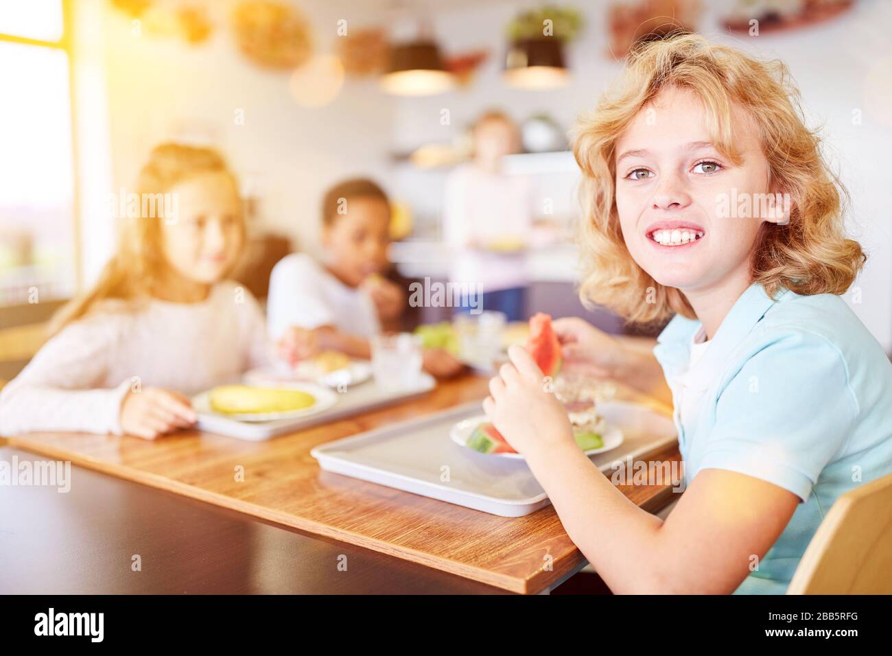 Happy children eat fruit together in a school cafeteria Stock Photo Alamy