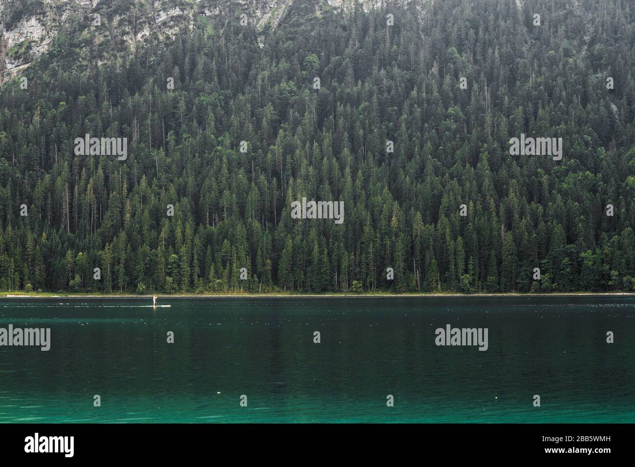 A man practising SUP or Stand Up Paddle surf board in Eibsee lake in