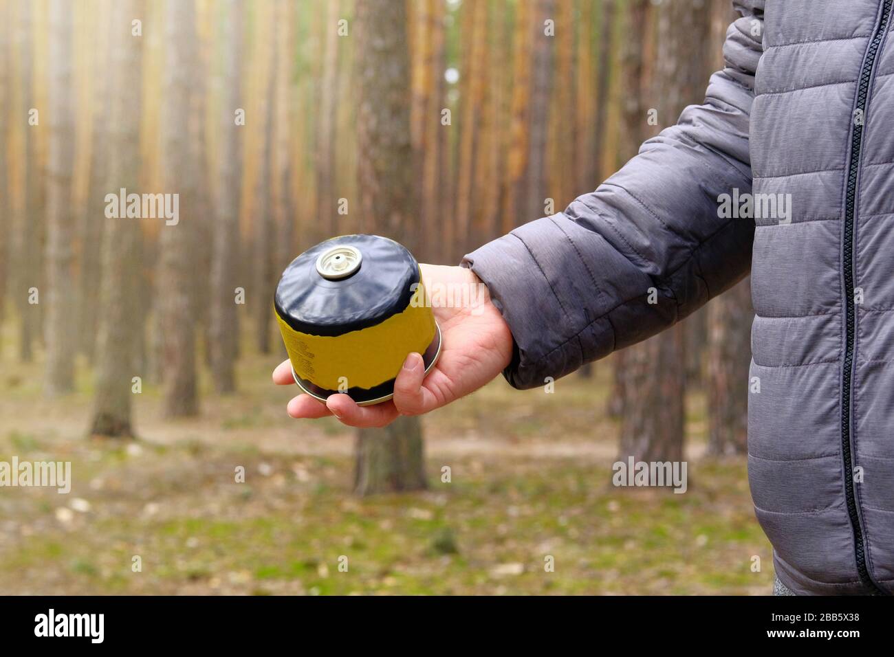 Cylinder for a gas burner in a tourists hand. Food during hiking trips. Enjoy a tasty food during camping. Stock Photo