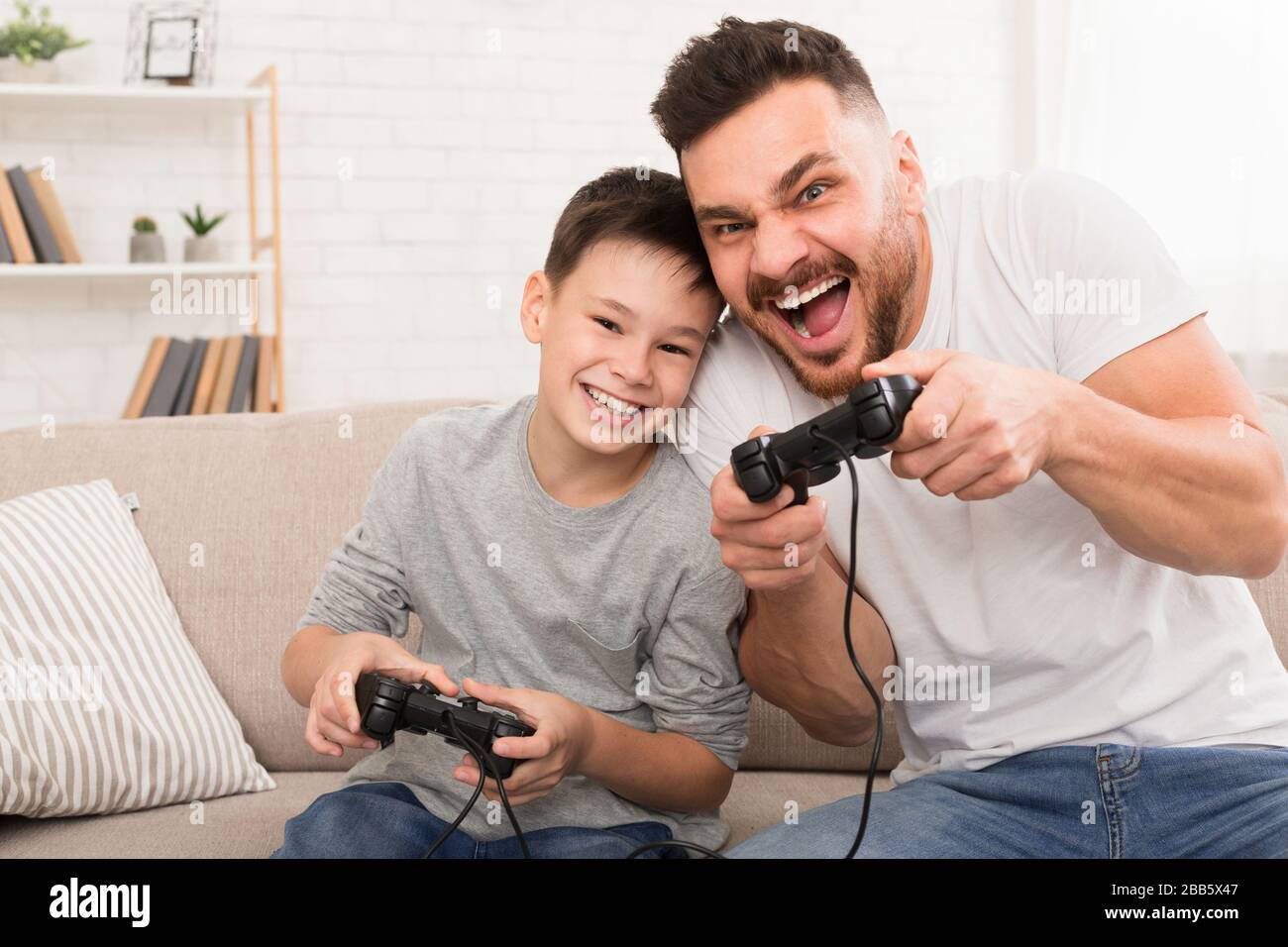 Dad and son with joysticks playing video games at home Stock Photo