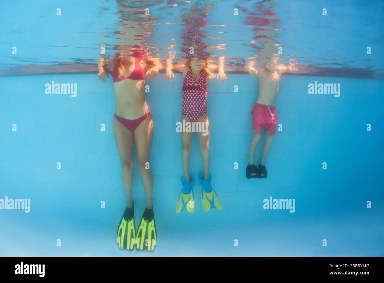 Happy family has fun, relax at poolside after swimming lesson. Underwater photo of people group in pool. Healthy lifestyle, active parents Stock Photo