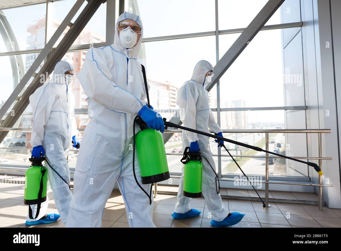 Professional workers in hazmat suits disinfecting indoor accommodation ...