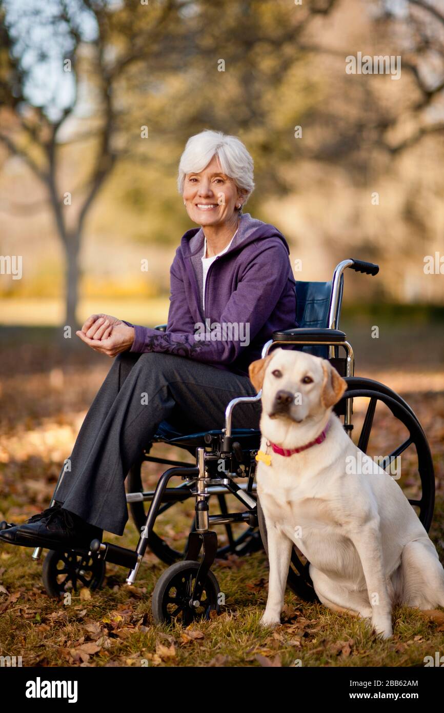 Portrait of a smiling senior woman sitting in a wheelchair next to her ...