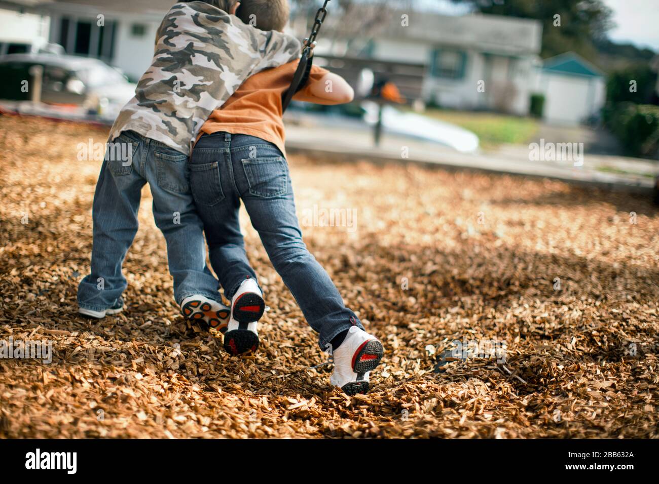 Two young boys playfully fighting for the same swing at the playground. Stock Photo