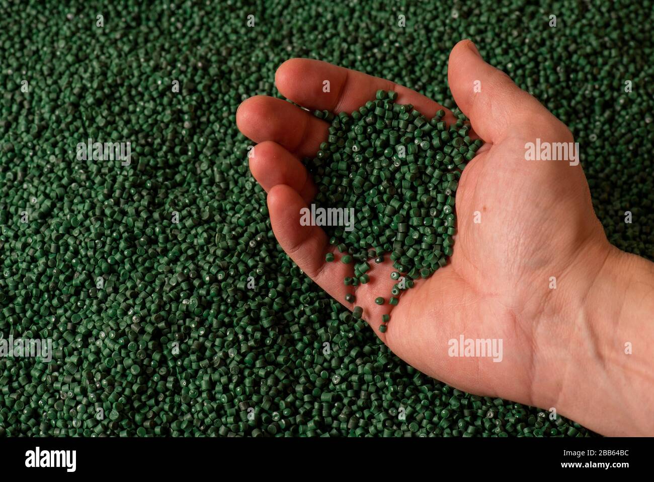 Granular recycled green plastic in hand Stock Photo Alamy