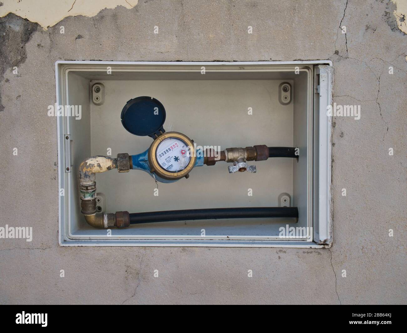 A domestic water supply meter and shut off valve in an external wall outside a house in Funchal, Madeira. Stock Photo