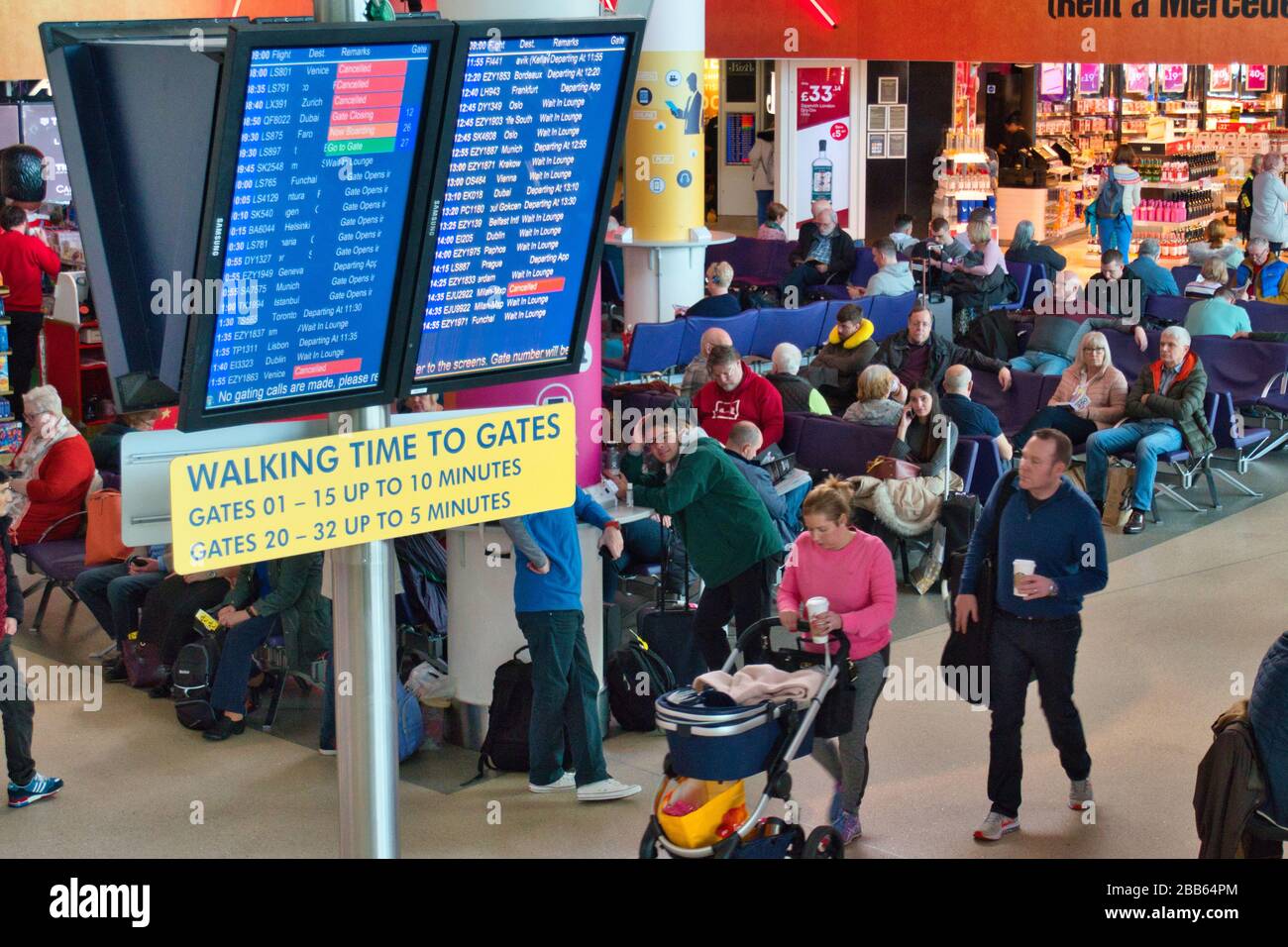 Flight departure information screens and travellers in the departure lounge at Manchester
