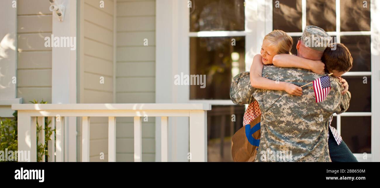 Army soldier hugging his two young children on the steps of their home