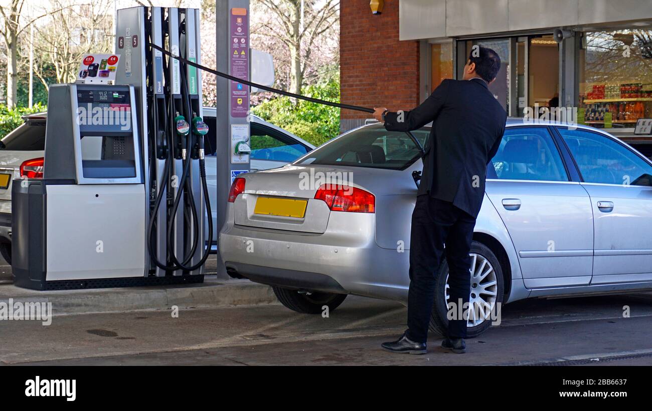 A man refilling his car with fuel at a petrol or gas station Stock Photo