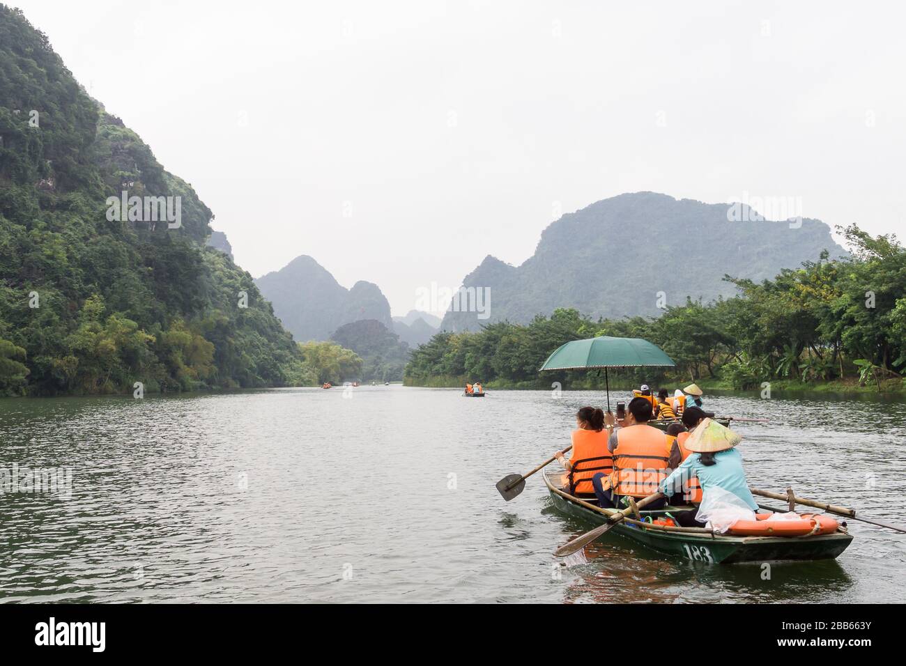 Vietnam Trang An Landscape Complex - Rowboat with tourists enjoying the landscape in Trang An in Ninh Binh Province of North Vietnam. Stock Photo