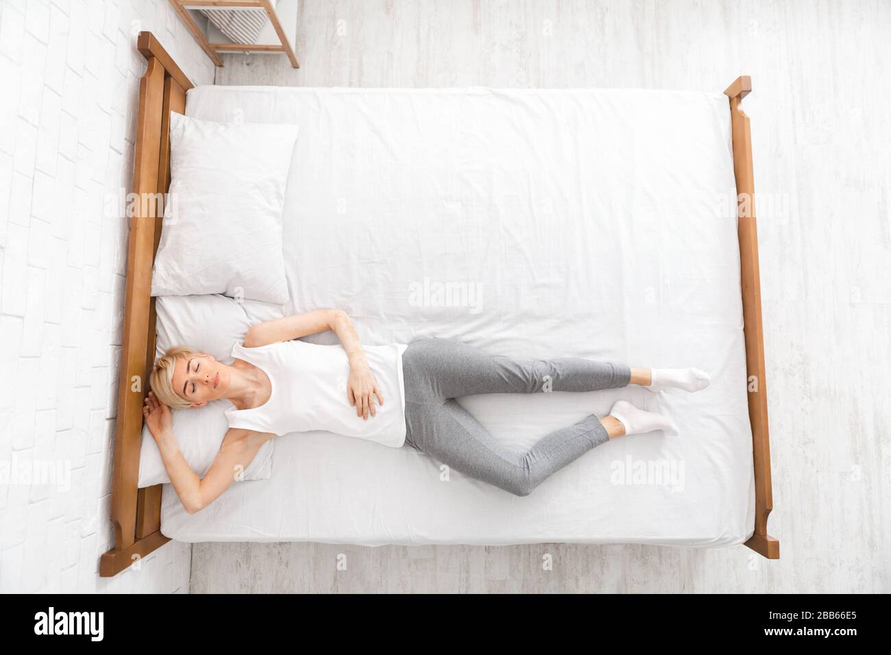 Top view of woman lying in bed with closed eyes Stock Photo