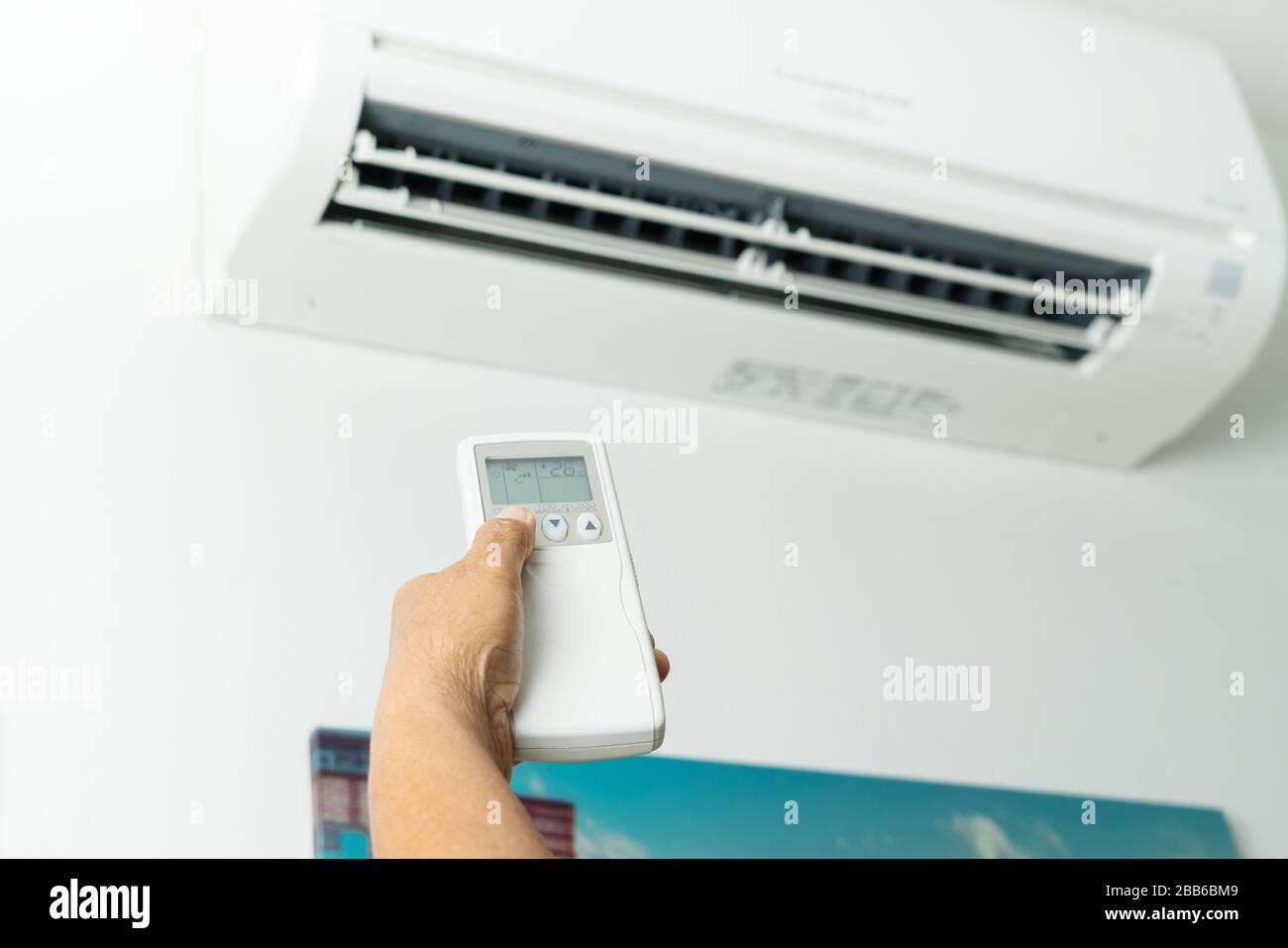 Remote control directed on air conditioner systrem, senior hand control air conditioner at home Stock Photo