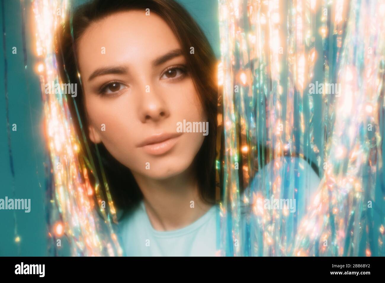 Portrait of a beautiful woman looking through a tinsel curtain Stock Photo