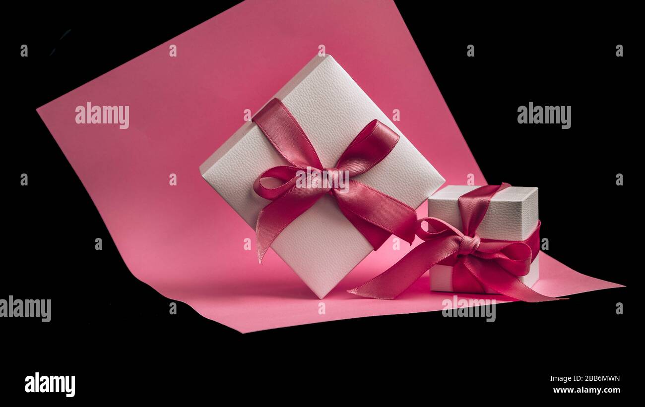 Present box with pink ribbon on the pink and black background Stock ...