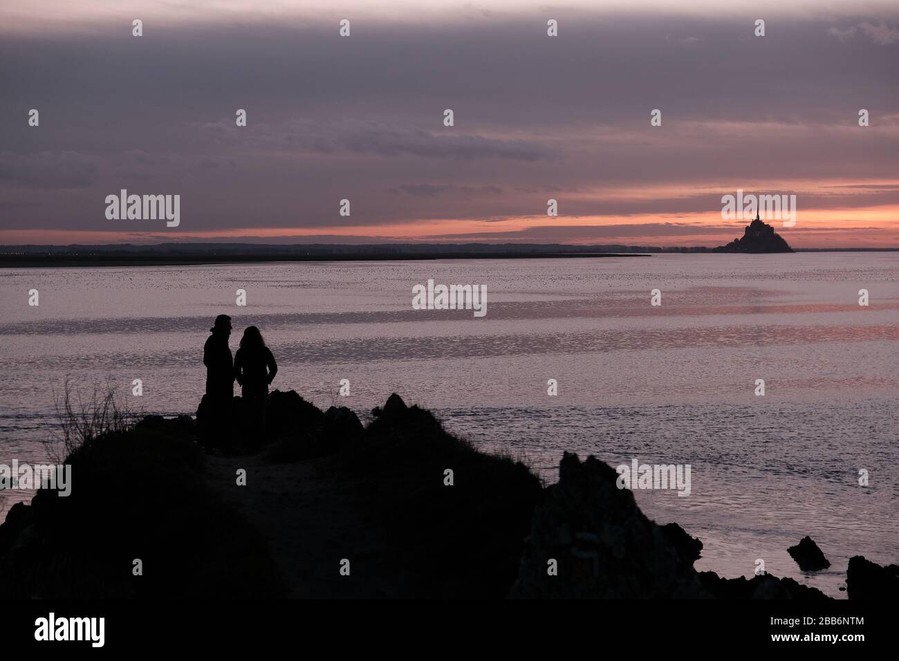 Silhouette of a couple looking at Mont Saint Michel, Normandy, France Stock Photo