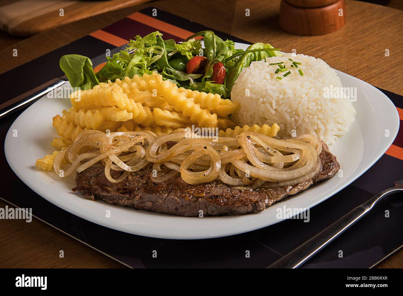Steak with fried onions, rice, French fries and salad Stock Photo