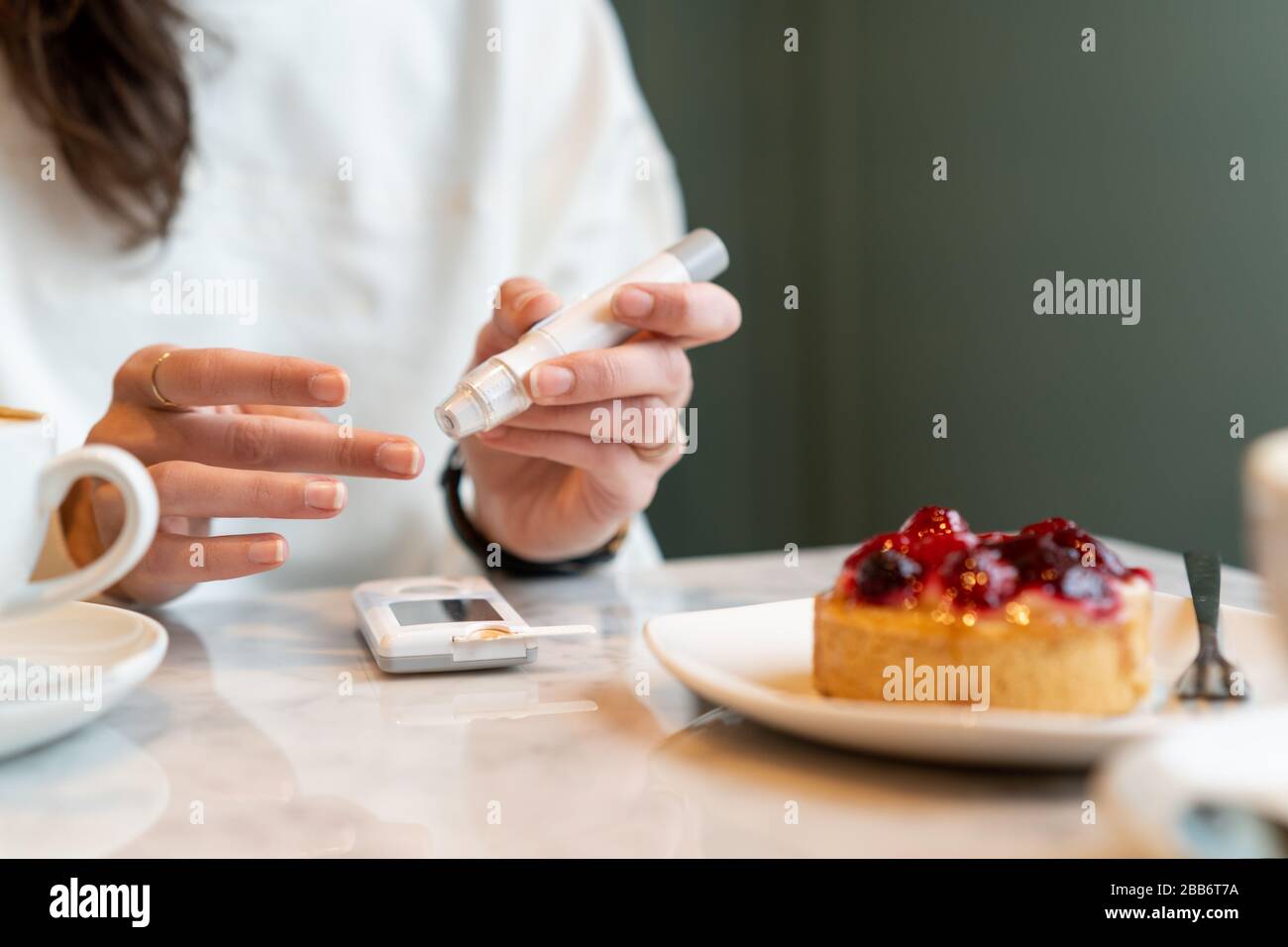 Woman checking her insulin levels before eating a cake Stock Photo